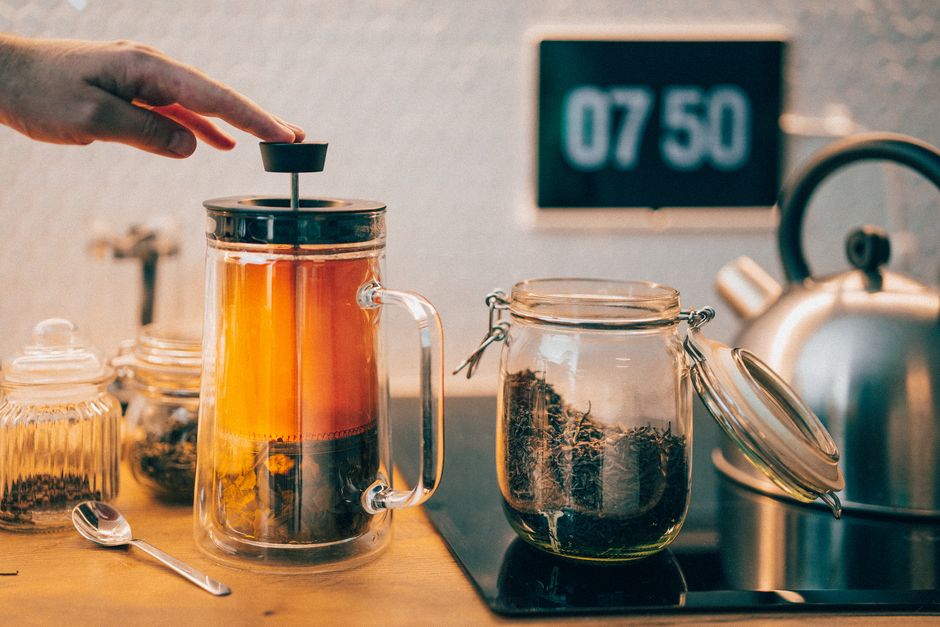 A cozy kitchen scene of a hand brewing tea with a French press, perfect for lifestyle content.
