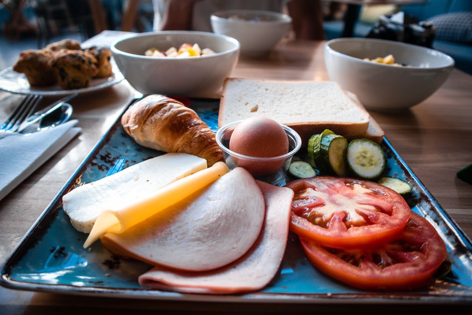 A delectable European breakfast spread featuring bread, cheese, and fresh vegetables on a tray.