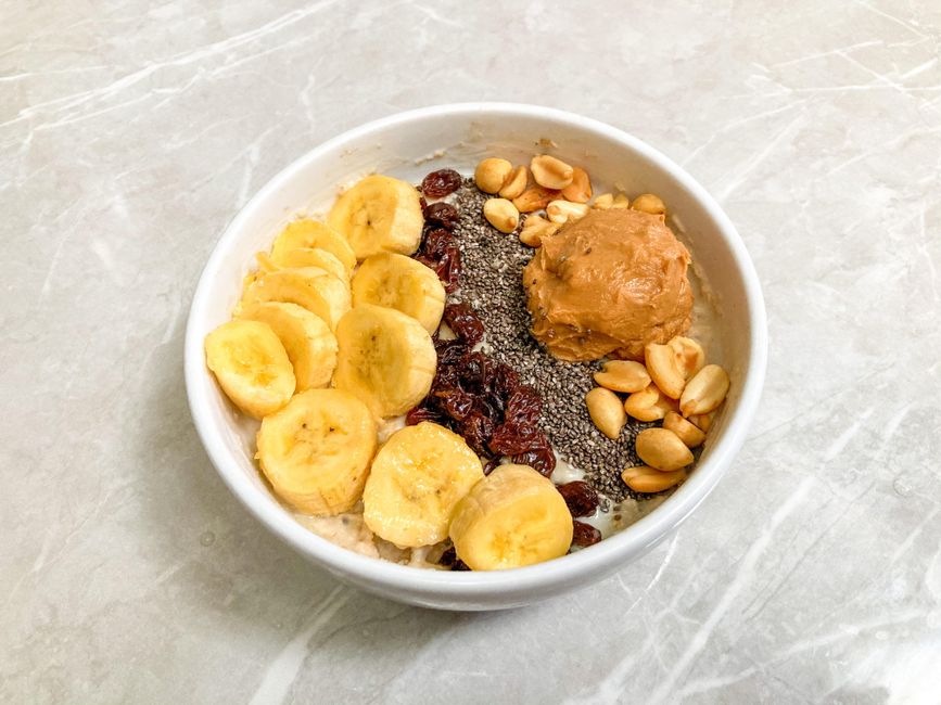 A delicious breakfast bowl with bananas, chia seeds, peanuts, raisins, and peanut butter.