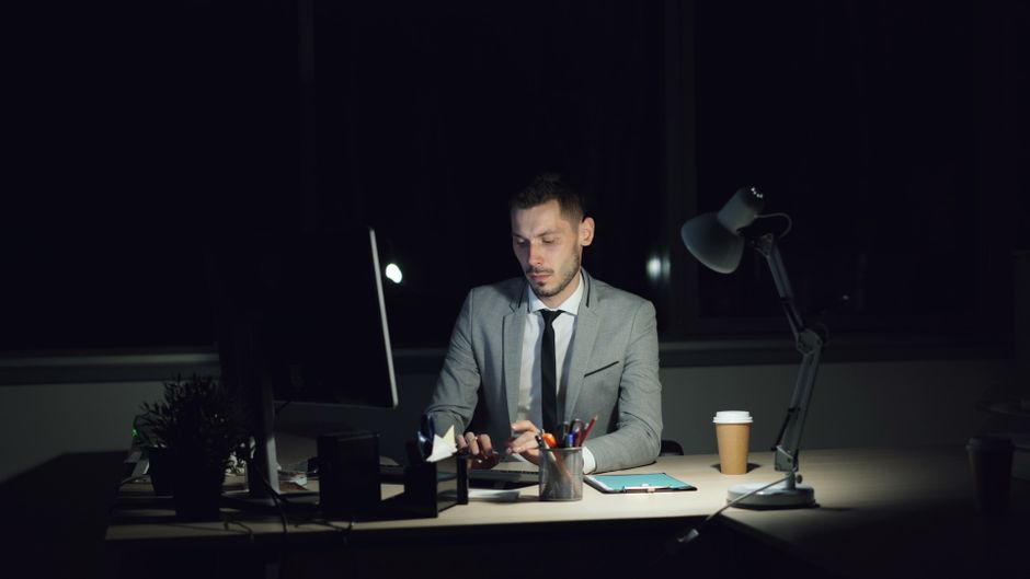 A focused businessman working late in a dimly lit office at night.