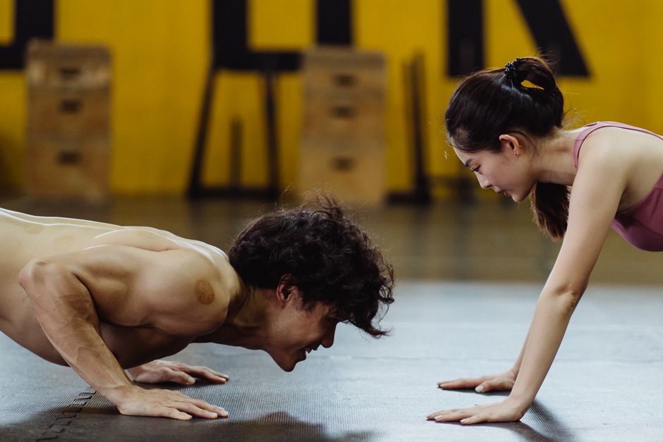 A focused couple performing push-ups together indoors, highlighting fitness and motivation.