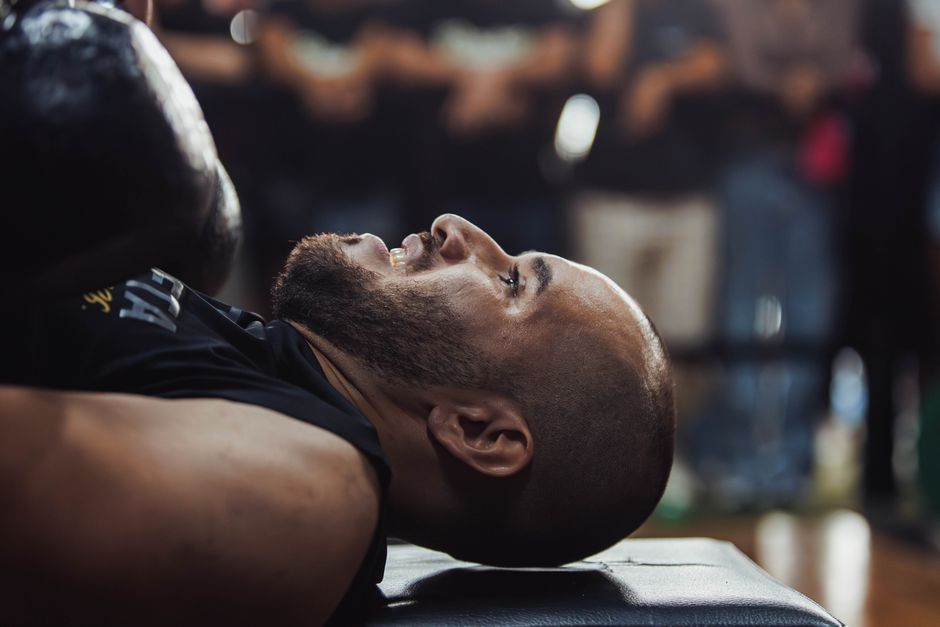 A focused view of a man lying down in a gym setting, indicating post-exercise relaxation.