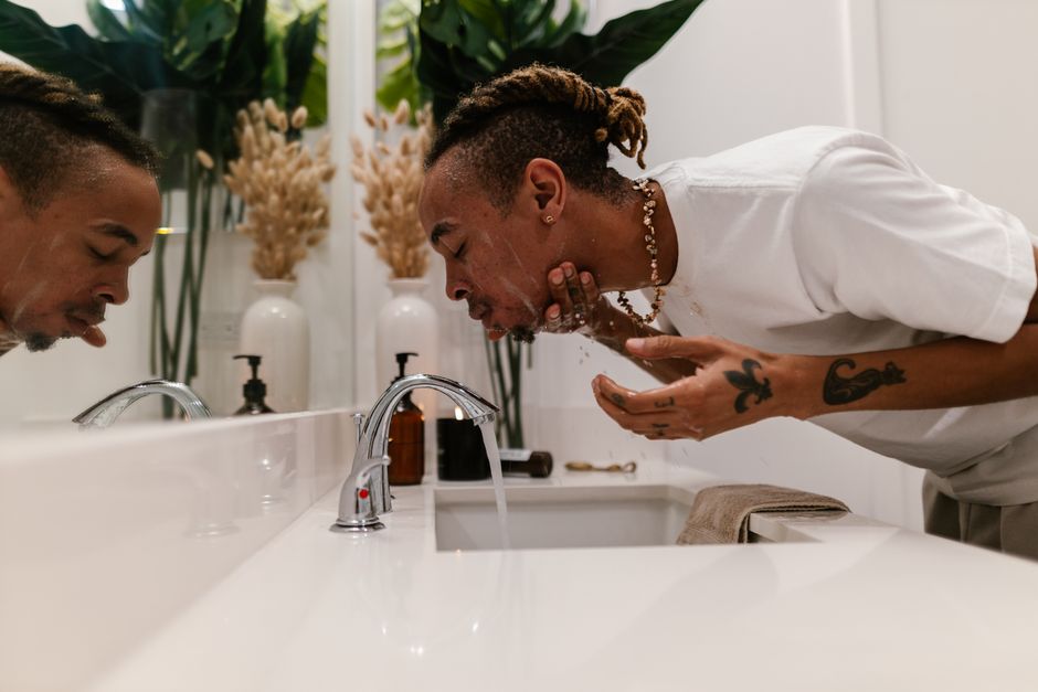 A man cleansing his face in the bathroom as part of a morning skincare routine.