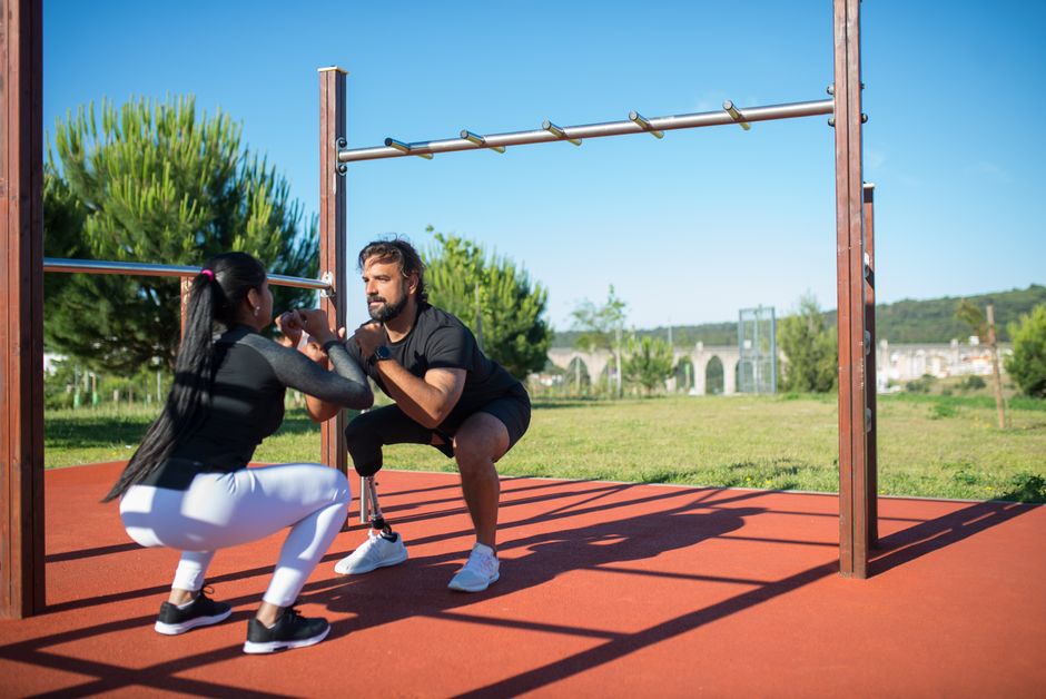 A man with a prosthetic leg and a woman exercise outdoors in Portugal, showcasing adaptive fitness.