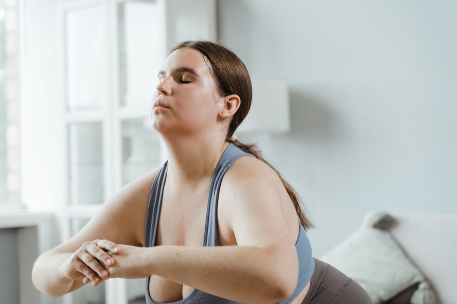 A plus size woman practicing yoga indoors with focus on wellness and relaxation.