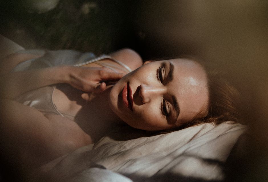 A serene close-up of a woman relaxing peacefully in soft morning light, emphasizing tranquility.
