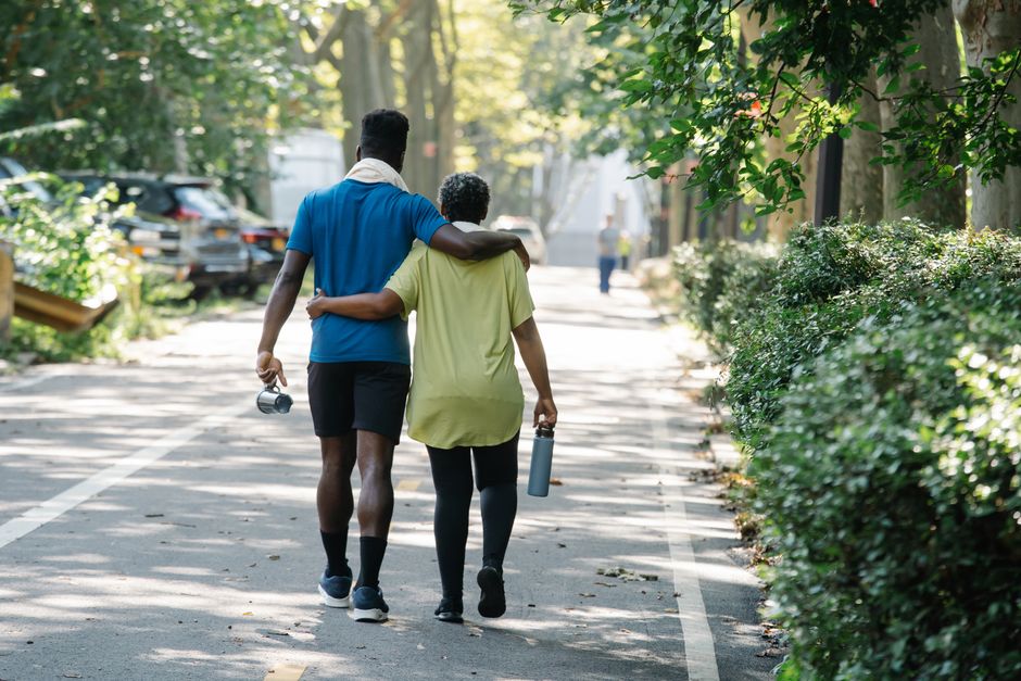 A serene moment as a mother and son walk arm-in-arm down a tree-lined path.