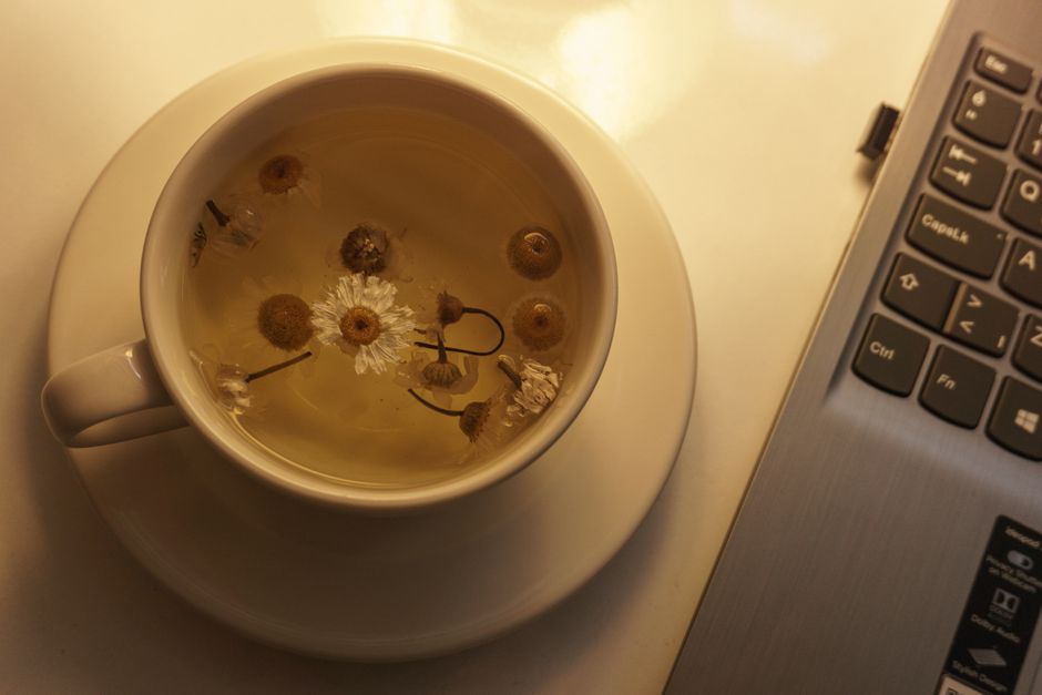 A soothing cup of chamomile tea next to a laptop, perfect for relaxation or work breaks.