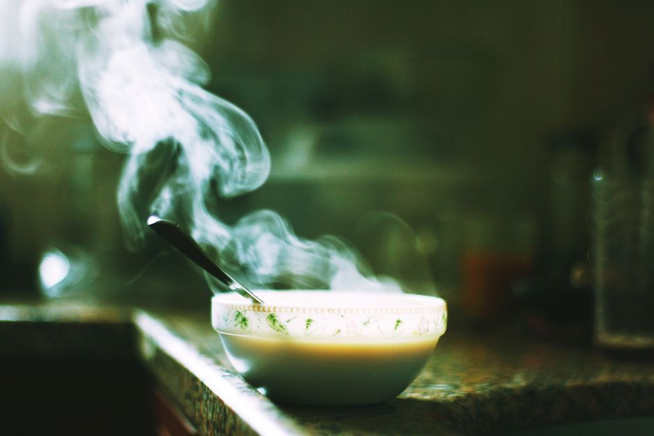 A steaming bowl of soup sits on a kitchen counter, emitting warm wafts into the air.