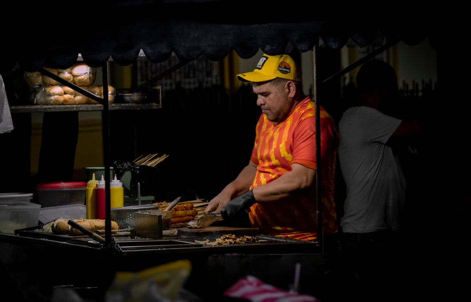 A street vendor prepares food at a night market stall, showcasing a vibrant urban scene.