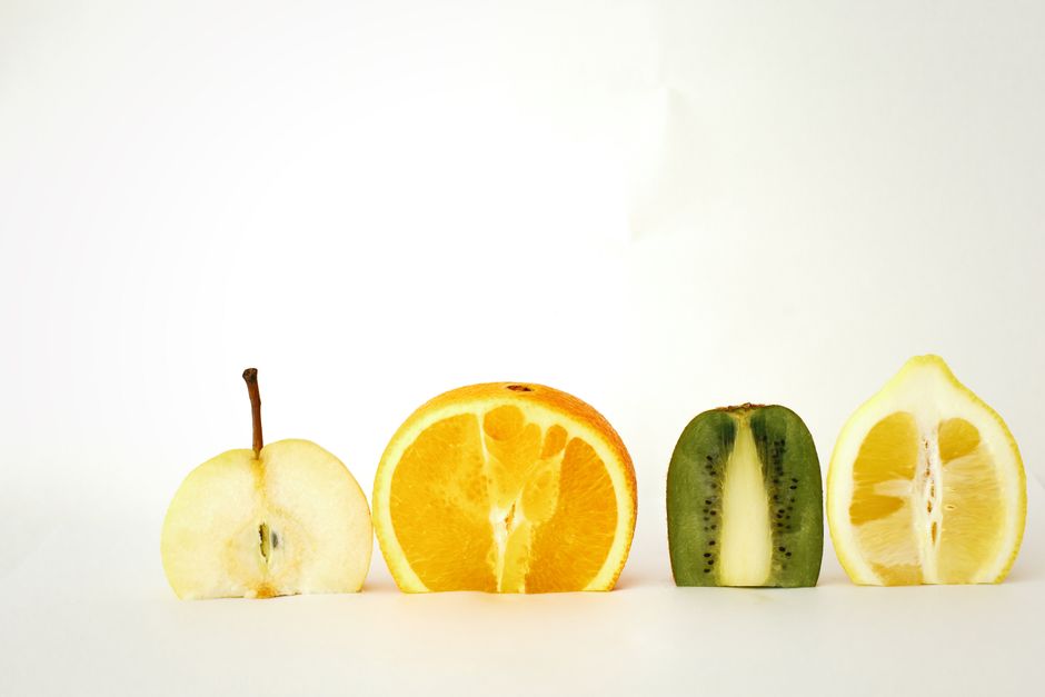 A variety of colorful sliced fruits displayed in a minimalist style against a white backdrop.