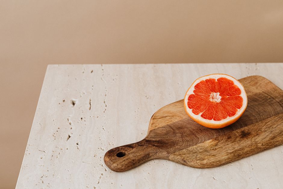 A vibrant halved grapefruit displayed on a rustic wooden cutting board.