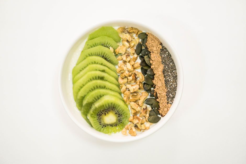 A vibrant smoothie bowl with kiwi, nuts, seeds, and yogurt, ideal for a nutritious breakfast.
