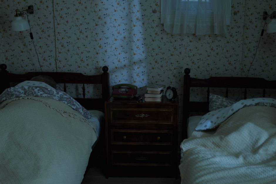 A vintage bedroom setting with two people sleeping under dim lighting, creating a tranquil nighttime feel.