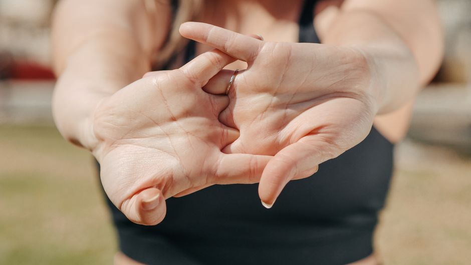 A woman's hands stretching outdoors, highlighting relaxation and fitness concepts.
