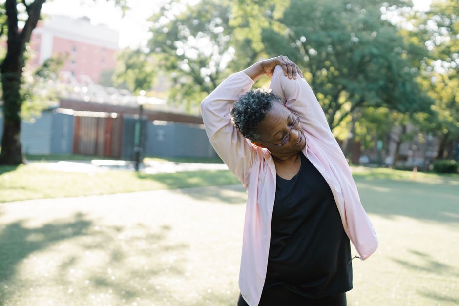 African American woman in a park doing stretching exercises on a sunny day.