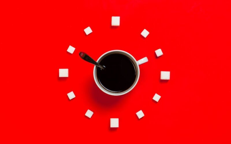 Artistic coffee composition with sugar cubes on a striking red background, from above.