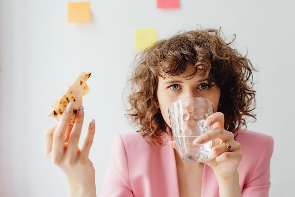 Businesswoman having a snack and water break in a home office setting. Vibrant, productive atmosphere.