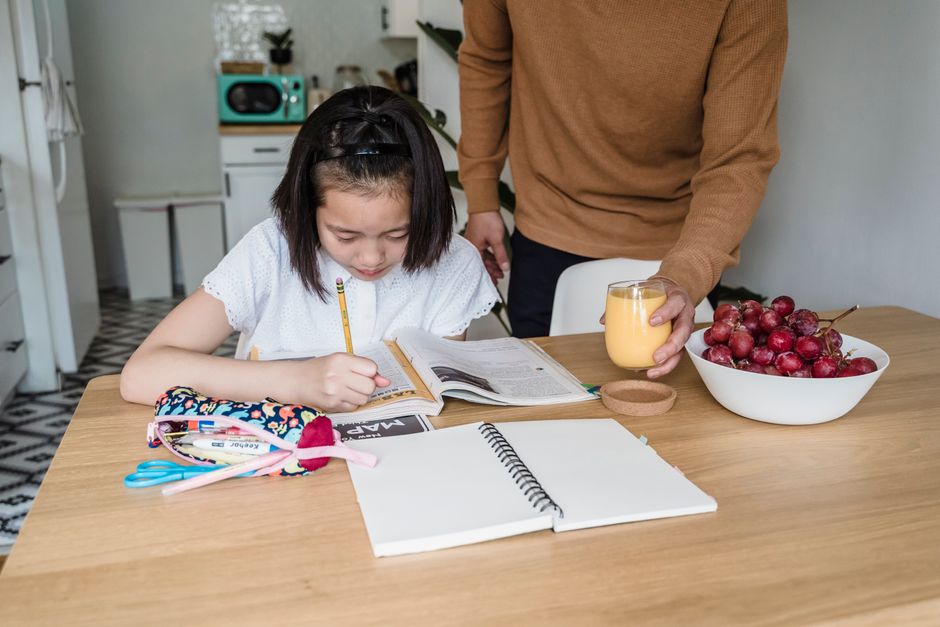 Child doing homework at home with a parent nearby, promoting learning and education.
