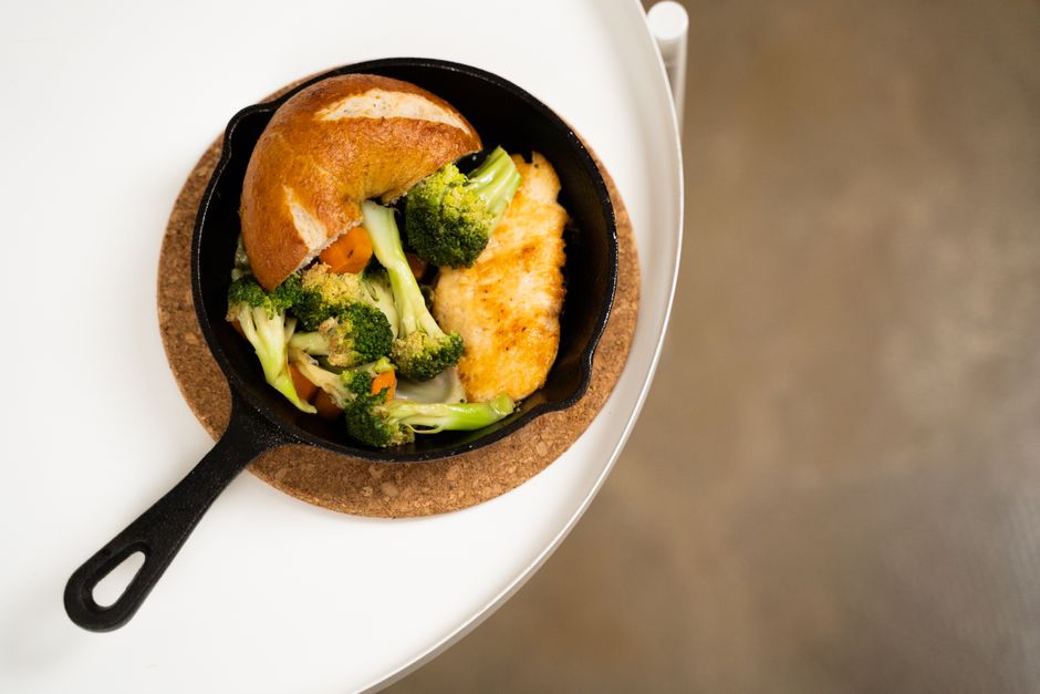 Close-up of a chicken skillet with broccoli, carrots, and bread, perfect for a healthy meal.