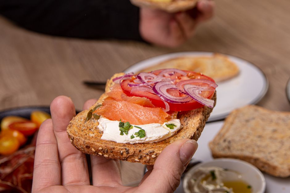 Close-up of a smoked salmon sandwich with cream cheese and veggies, perfect for healthy breakfasts or snacks.