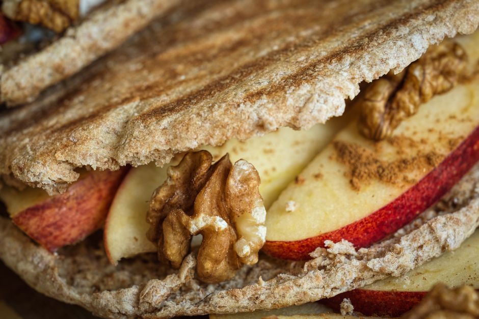 Close-up of a whole-grain pita sandwich filled with apples and walnuts.