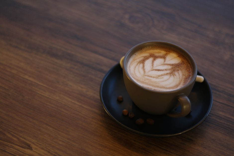 Close-up of an artistic latte with coffee beans on a wooden table, perfect for coffee lovers.