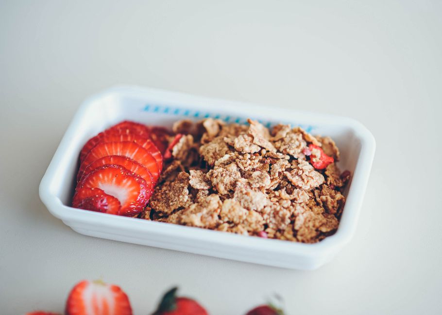 Close-up of crunchy granola and sliced strawberries in a white bowl, perfect for a healthy breakfast.