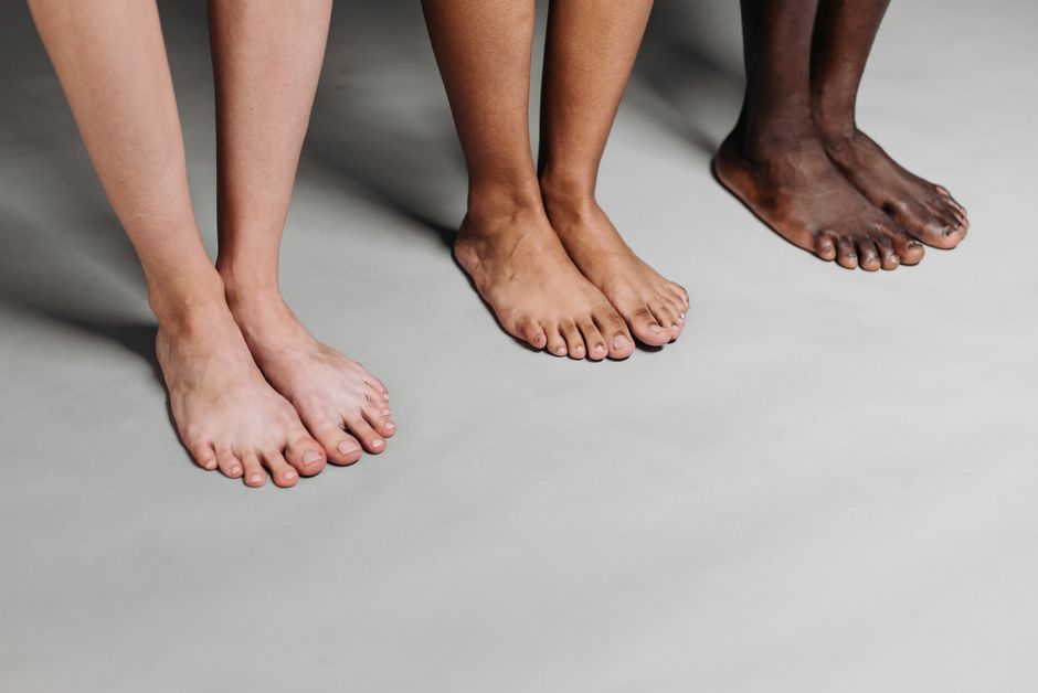 Close-up of diverse barefoot feet in a studio setting on neutral background.