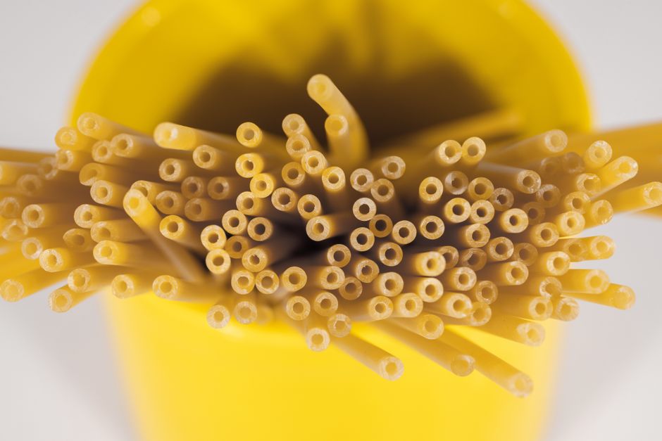 Close-up shot of raw pasta in a vibrant yellow container, emphasizing texture and color.