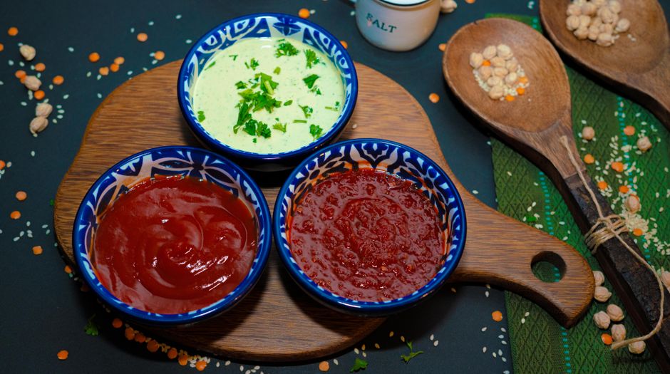 Colorful assortment of sauces in blue ceramic bowls on a wooden board, perfect for snacks.