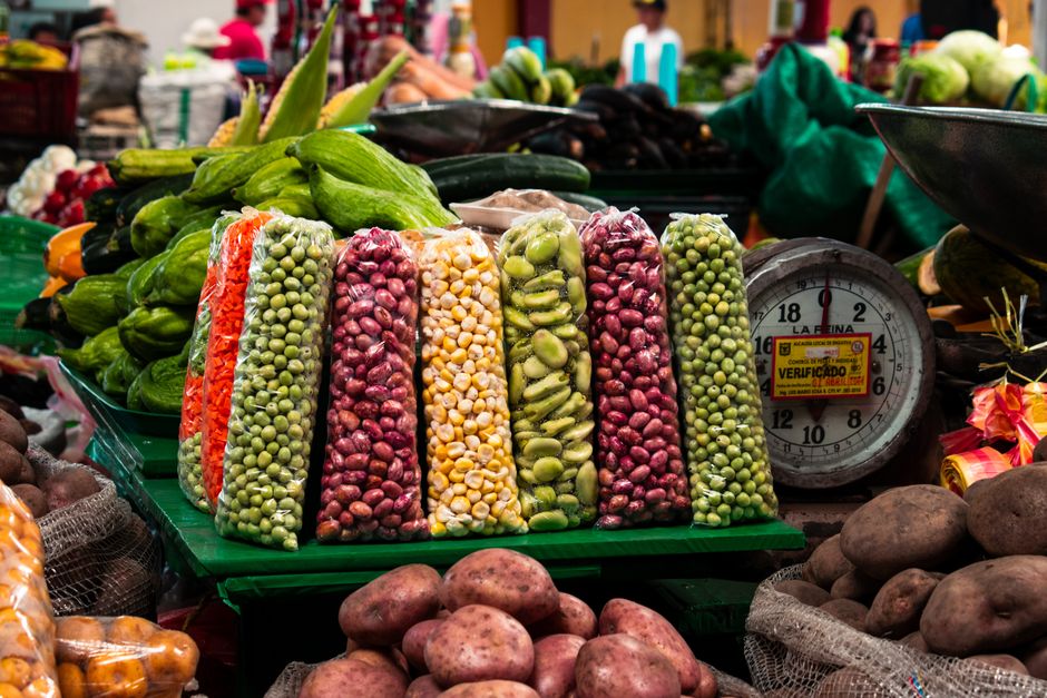 Colorful display of fresh vegetables and beans in a traditional market setting.