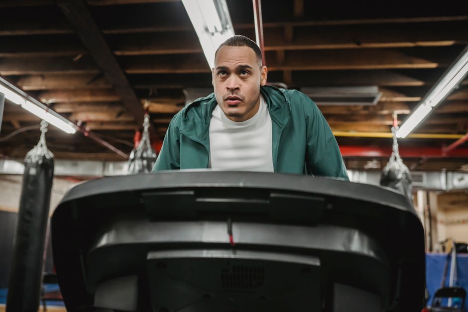 Concentrated male in sportswear training on treadmill and losing weight in contemporary sport club