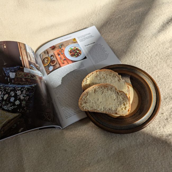 Cozy breakfast scene with sliced bread and an open magazine on a sunny morning.
