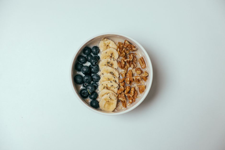 Delicious oatmeal bowl topped with blueberries, bananas, and walnuts.