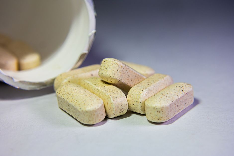 Detailed image of oblong tablets from a container, showcasing their texture and color.
