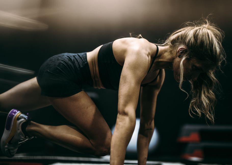 Focused female athlete in active pose working out at a gym in dynamic lighting.