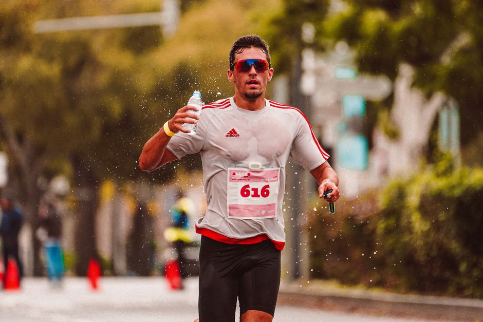 Focused runner splashes water during marathon in vibrant outdoor setting.