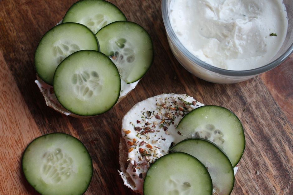 Fresh cucumber slices on creamy cheese bagel for a delicious snack.