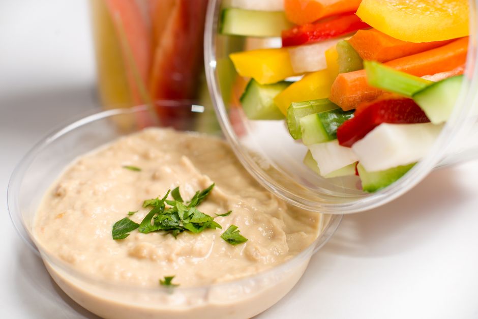 Fresh vegetable sticks with creamy hummus dip, garnished with parsley.