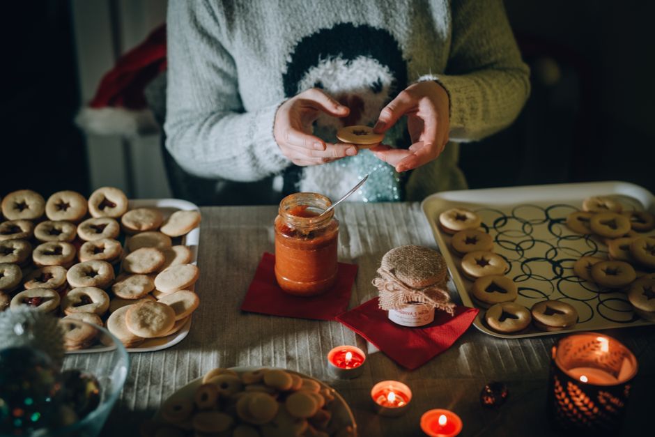 Freshly baked Christmas cookies being prepared with jam in a cozy setting.