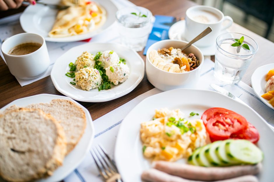 From above of tasty brunch of power bowl and scrambled eggs with fresh vegetable slices against drinks on table