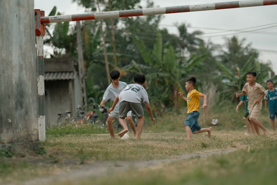Group of children playing soccer on a rural field, enjoying outdoor activity.