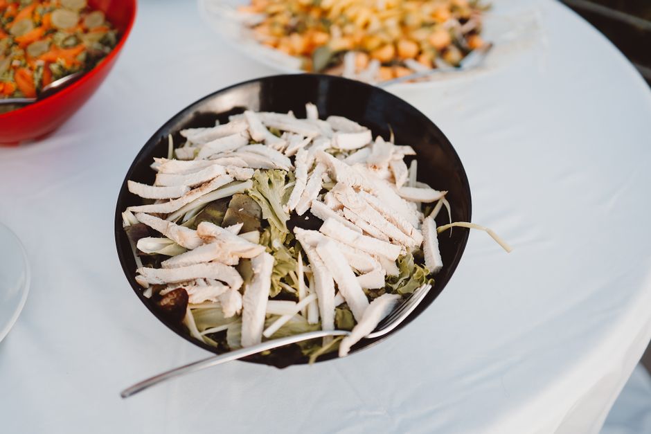 High-angle view of fresh chicken salad with greens in a black bowl. Perfect for health and food photography.