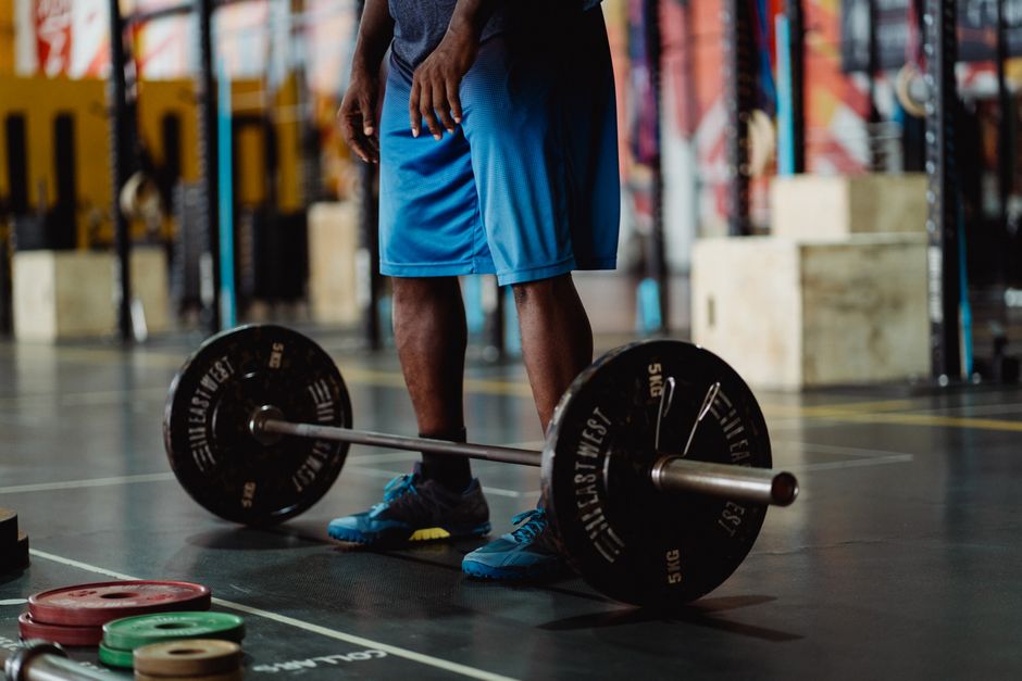 Man preparing for a weightlifting session with barbell and weights in a modern gym.