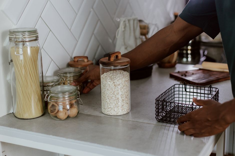 Modern kitchen counter with glass jars of pasta and walnuts, showcasing organization.