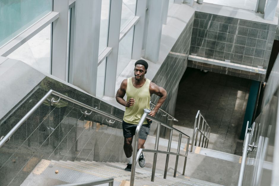 Muscular man in activewear running upstairs inside a modern building. Fitness concept.