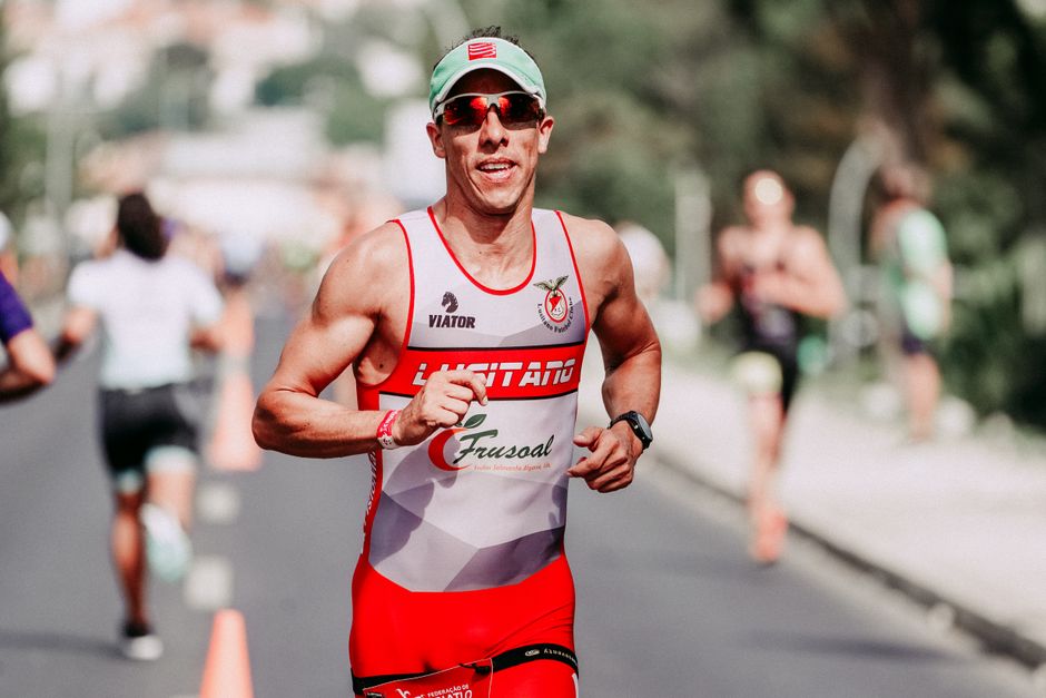 Muscular man in sportswear and glasses running on road and smiling during marathon