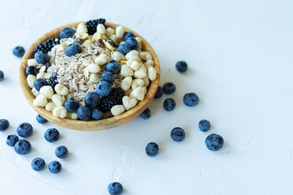 Nutrient-rich breakfast bowl with oats, blueberries, and puffed grains on a white background.