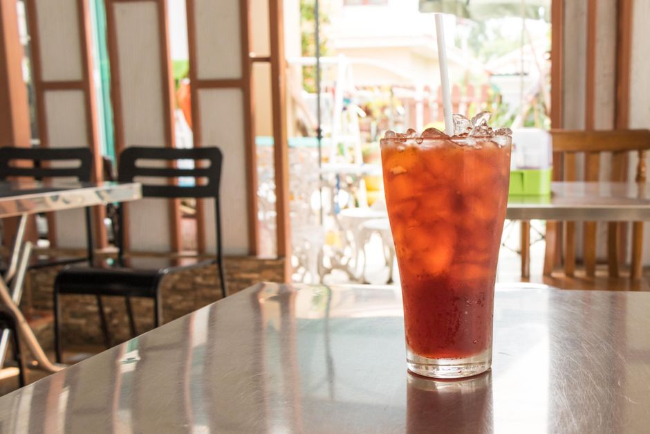 Refreshing iced tea in a glass with straw on a cafe table, perfect for summertime.